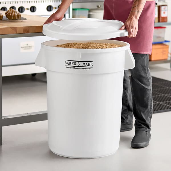 A large white round ingredient storage bin with a white lid labeled 'Baker's Mark,' shown filled with dry goods.