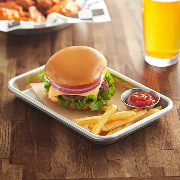 A Baker's Mark heavy-duty aluminum bun pan with a cheeseburger and fries on it.