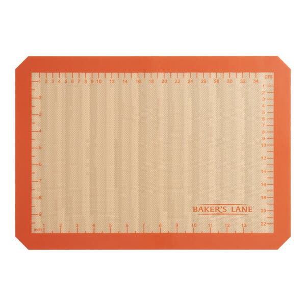 A close-up of a Baker's Lane orange silicone baking mat with measurements.
