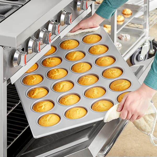 A person putting jumbo muffins in a Baker's Mark aluminized steel pan.
