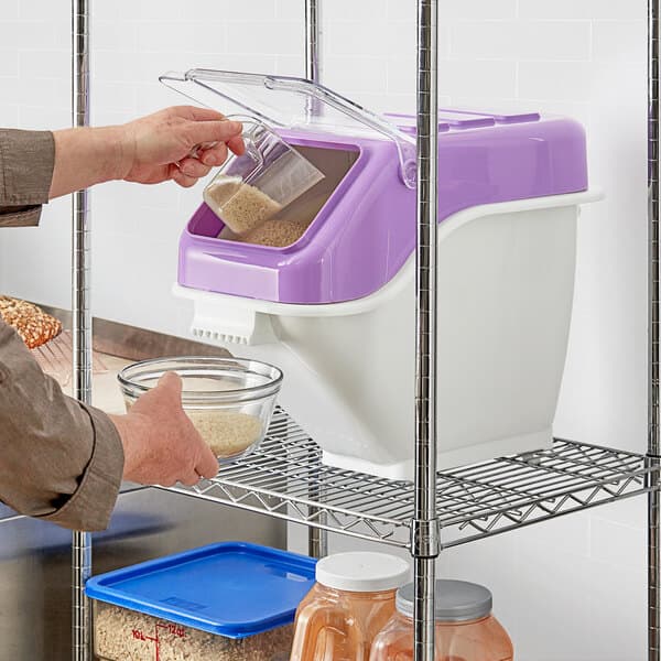 A person pouring rice into a white and purple Baker's Lane ingredient bin.