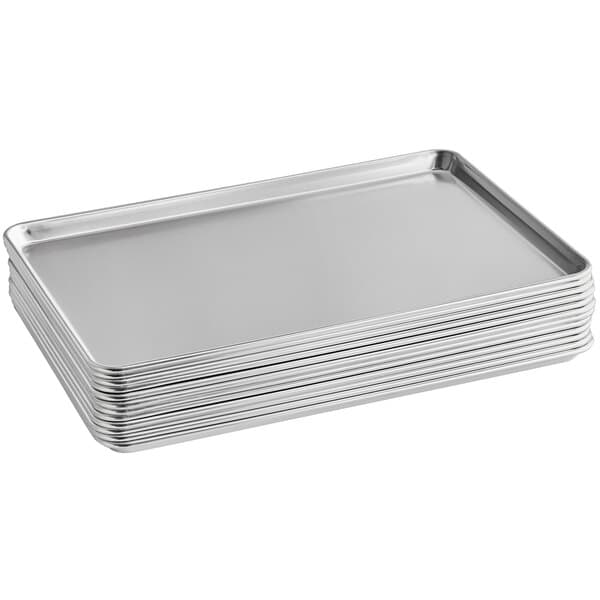 A stack of silver Baker's Mark aluminum bun/sheet pans on a counter.