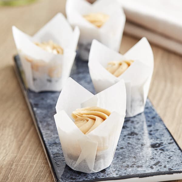 Three Baker's Mark white mini tulip baking cups with cupcakes on a plate.