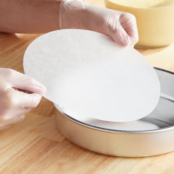 A person in gloves holding a Baker's Lane round white pan liner
