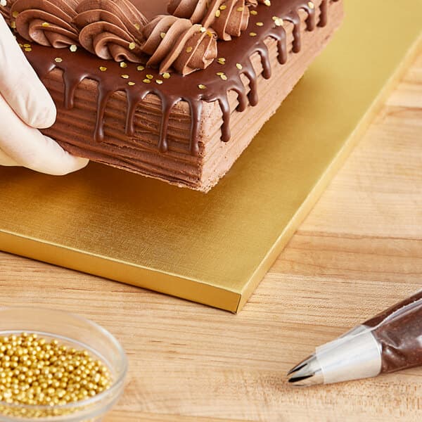 A chocolate cake on a Baker's Lane gold cake drum on a table