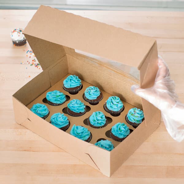 A Baker's Lane box of cupcakes with blue frosting on top.