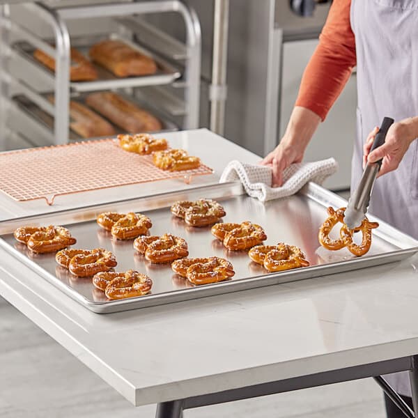 A woman using a Baker's Lane USA aluminum bun pan to bake pretzels.
