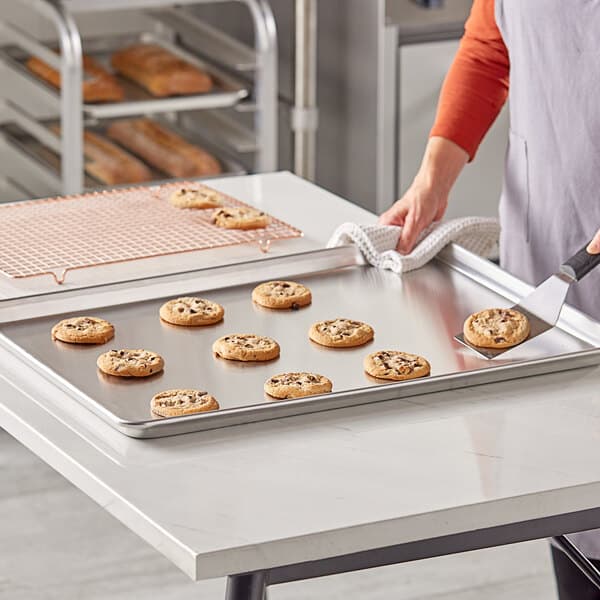 A woman using a Baker's Lane USA aluminum sheet pan to bake cookies.